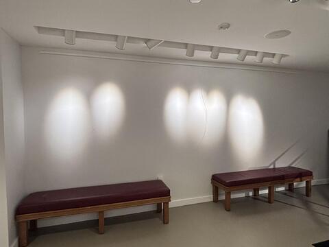 A white wall with six lights and two benches